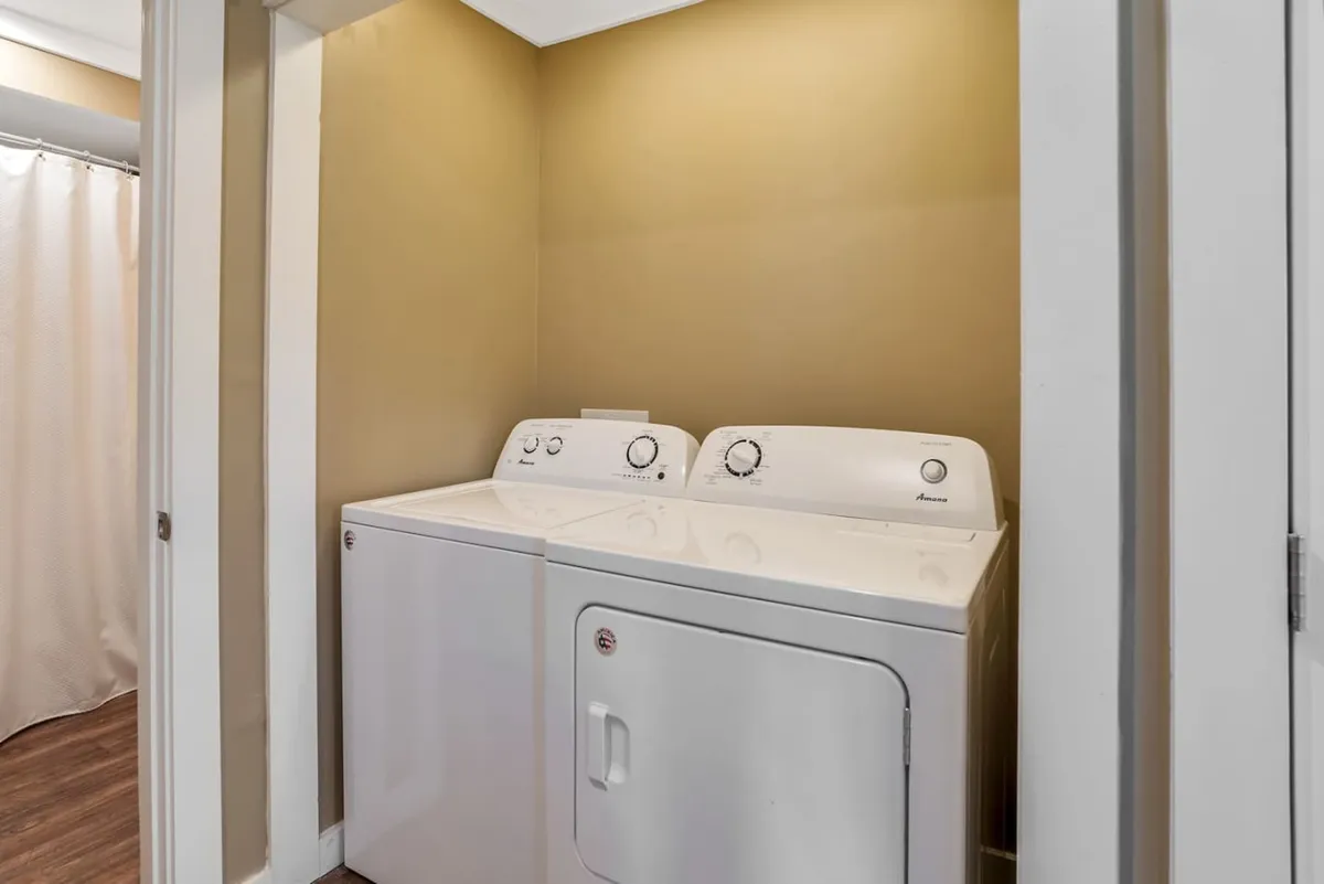 This image features an interior space focused on a washer and dryer setup, emphasizing practicality and comfort. The room is well-organized, with clean lines and a sense of calm created by neutral colors and soft lighting, reinforcing an atmosphere of restful domesticity.