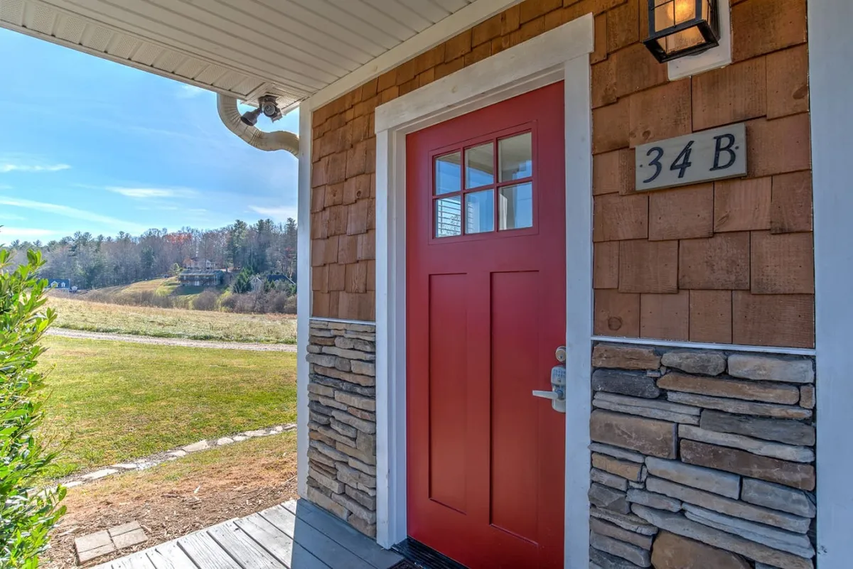 An exterior shot highlighting a welcoming red front door framed by stone accents and the home’s number. The inviting porch scene suggests a cozy, approachable atmosphere, hinting at the comfort within.